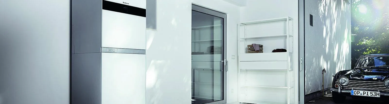 In einem modernen, hellen Hauswirtschaftsraum steht eine kompakte Wärmepumpe von Buderus mit digitalem Display. 