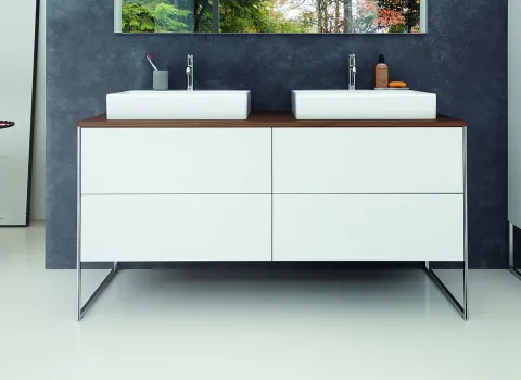 Ein stilvoller Waschtisch mit zwei Waschbecken, montiert auf einer Kommode aus weiß lackiertem Holz und dunkler Holzplatte.