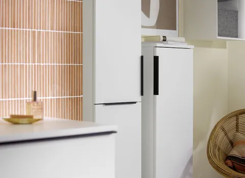 Ein Blick auf zwei hohe, weiße Schränke der Burgbad Eqio-Kollektion, die im Badezimmer nebeneinander platziert sind und sich durch ihre schlichte Ästhetik und schwarzen Griffe auszeichnen.