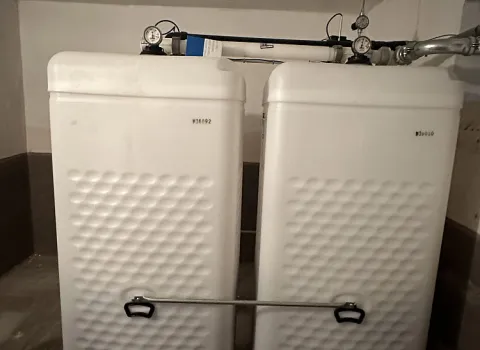 Zwei weiße Kunststofftanks mit Wabenstruktur stehen nebeneinander und bilden eine kompakte Öltankanlage.