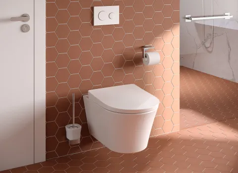 In einem zeitgemäß designten Bad ist ein TOTO GP Wand-WC an einer Wand mit terrakottafarbenen Sechseckfliesen montiert.