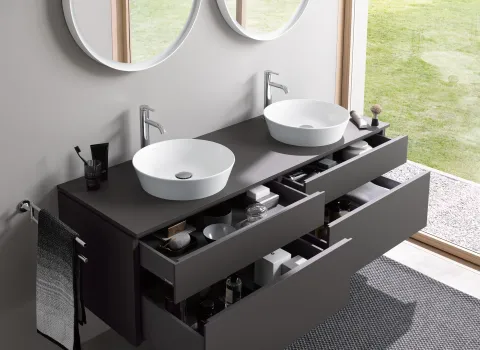 Doppelwaschtisch mit Waschbecken und Armaturen von Duravit, runden Spiegeln und modernen Badmöbeln vor bodentiefem Fenster.